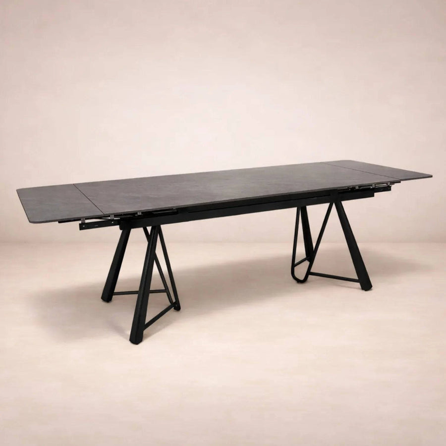 Mesa de comedor extensible de color gris oscuro con superficie de cerámica y base metálica, vista frontal.